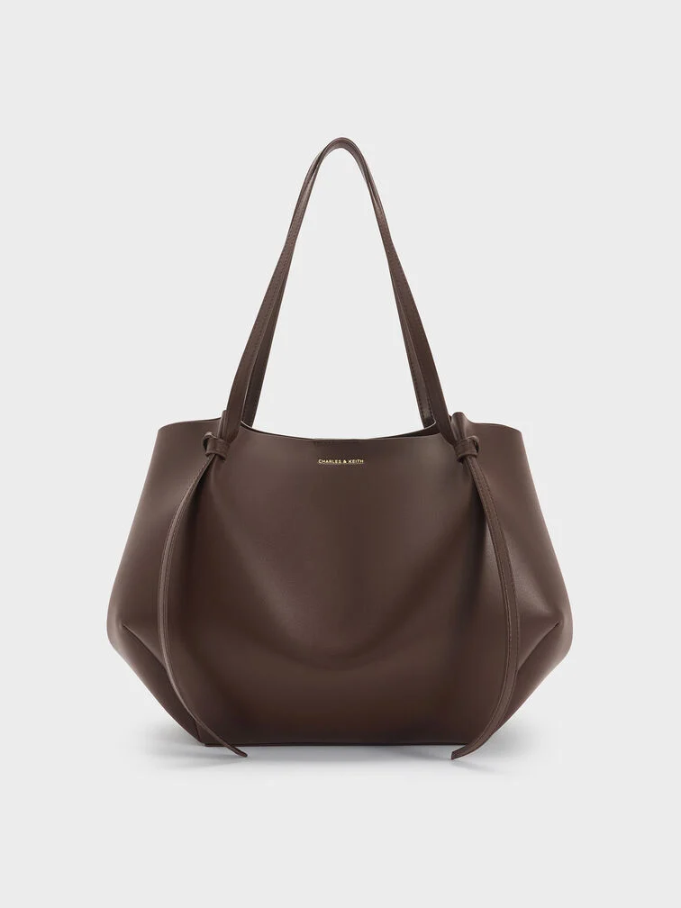 The XL Calla tote bag in espresso brown with the side magnetic clasps folded in to create a geometric-like shape